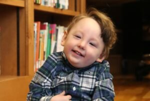 Smiling child posing for a photo in front of a bookshelf