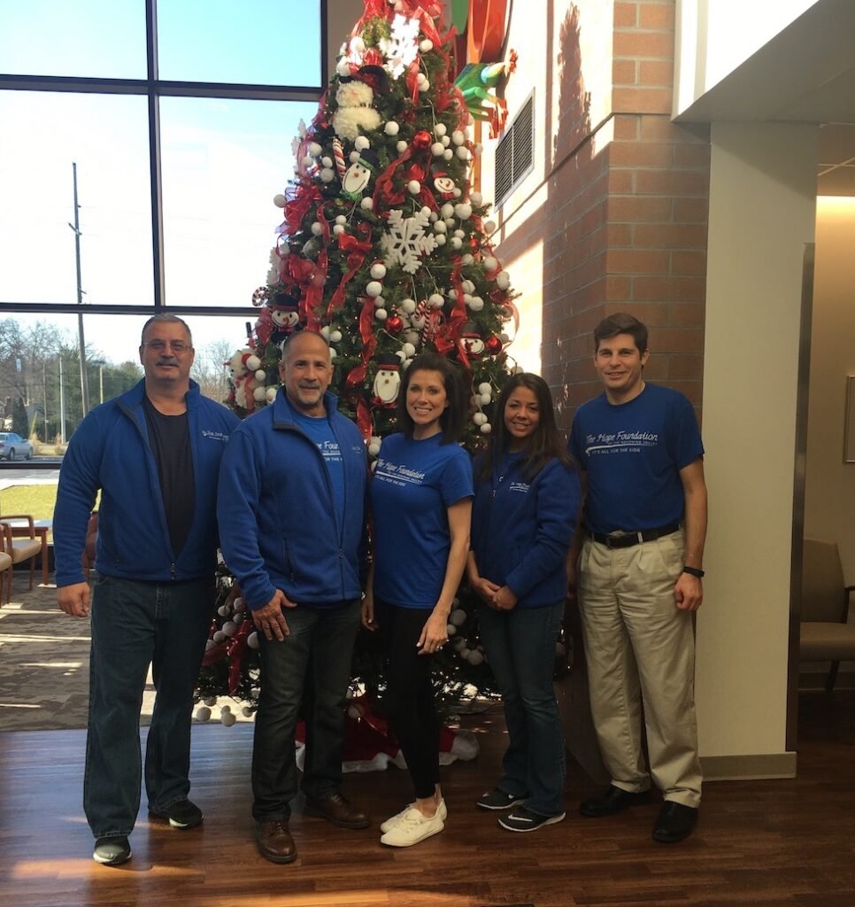 2018-12-02-13.25.27-1 - Hope Foundation of the Mahoning Valley Hope Foundation Members Posing In Front Of A Christmas Tree