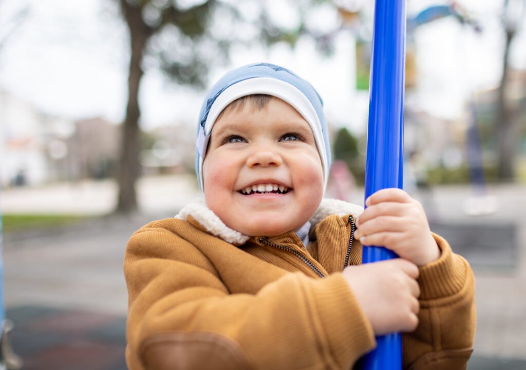 A boy on a playground in an autumn park rides on a swing in cloudy weather - Hope Foundation of the Mahoning Valley